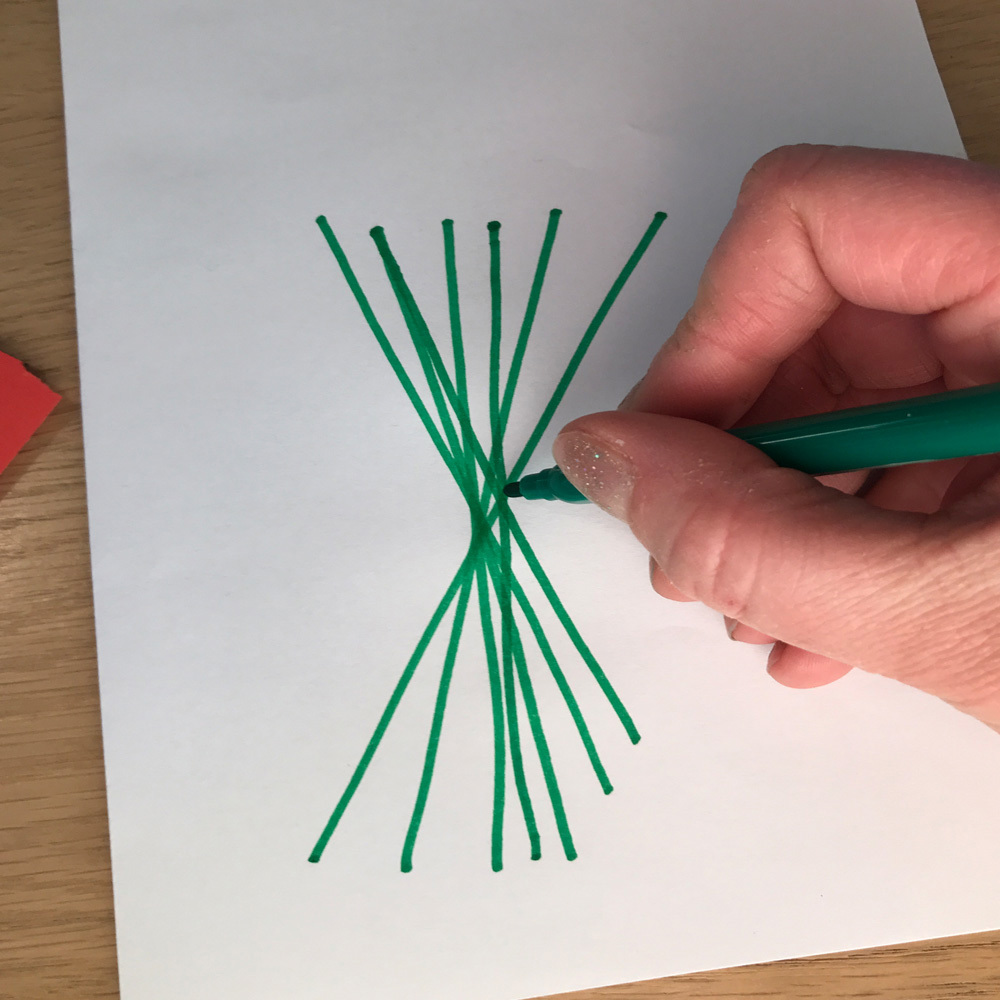 En hånd tegner streker på et ark. Foto