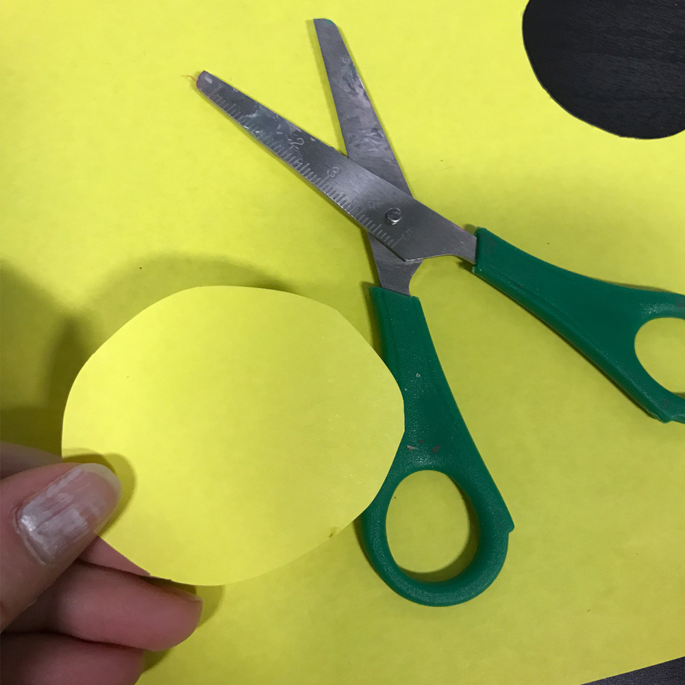 Vi klipper ut en gul sirkel i papir. Foto