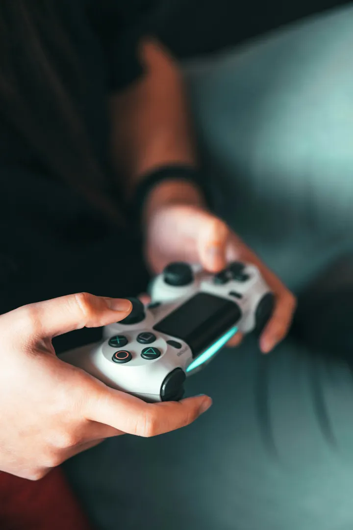 Nærbilde av hånd som holder en kontroller til PlayStation. Foto:  Sora Khan på Unsplash