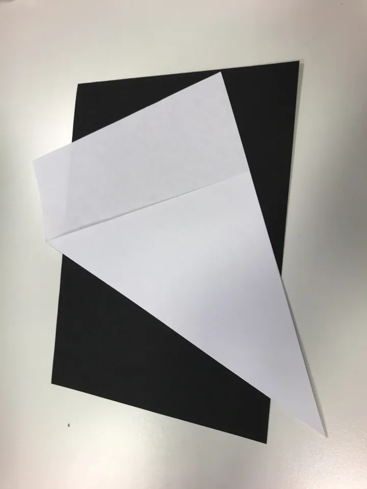 Et a4-ark er brettet slik at det blir en firkant med like sider, og en del av arket er klart for å bli klippet av. Foto