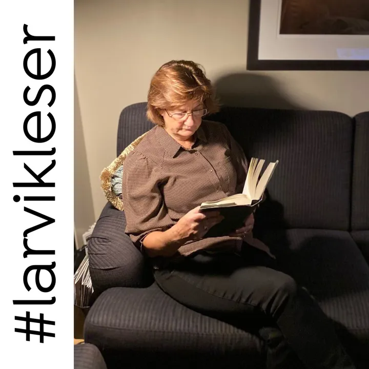 En kvinne sitter i en sofa og leser i ei bok. Foto