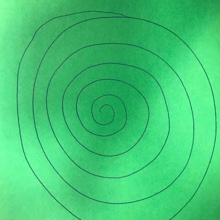 En spiral er tegnet opp på et grønt ark. Foto