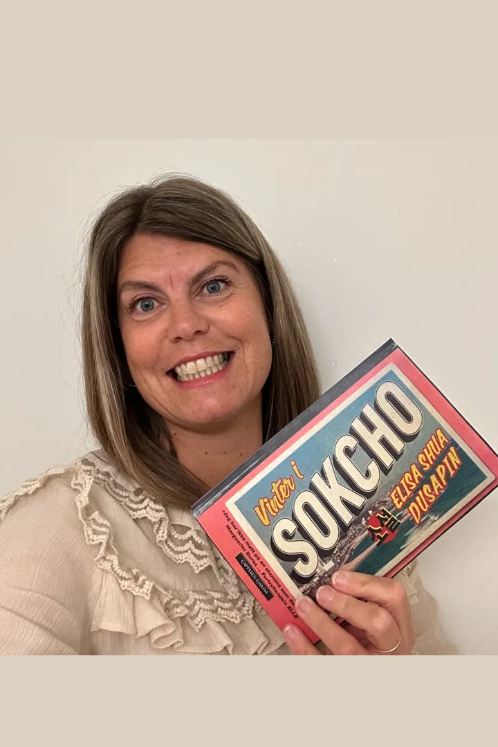 Foto av en av bibliotekets ansatte  som viser frem boka Sokcho.