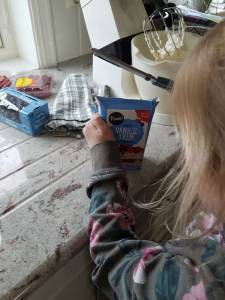 Et barn åpner en pakke vaniljekrem. Foto