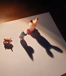 Tre små figurer kaster skygge på et papirark. Foto