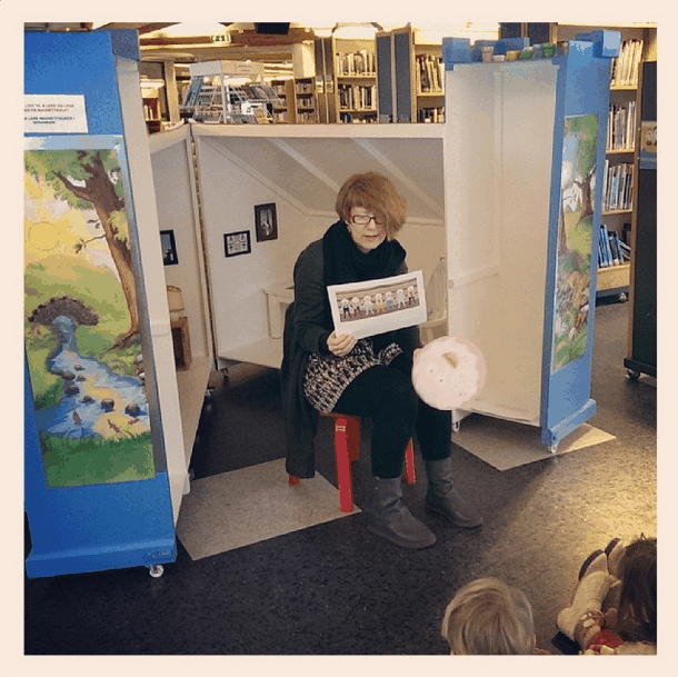 Kvinen sitter i grevlingens hus og leser fra en bok. Foto