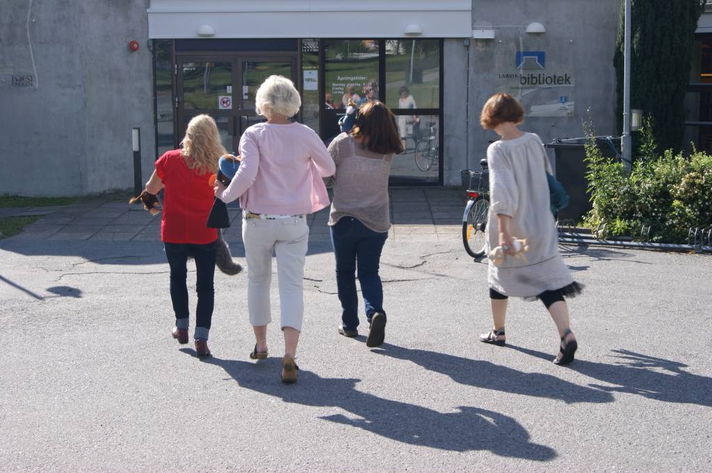 Fire damer på full fart mot inngangen, sett bakfra. Foto