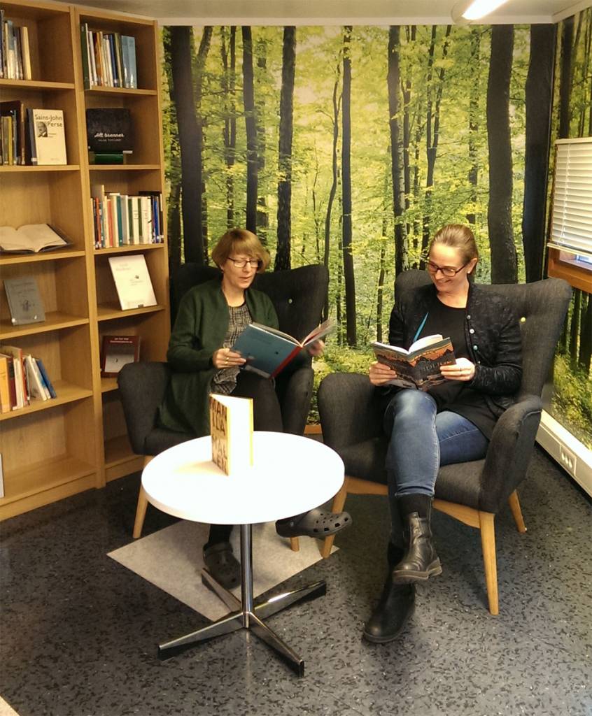 To damer leser i bøker, de sitter i hver sin stol. Foto