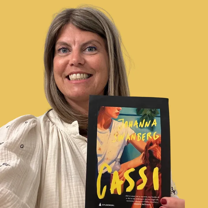 Foto av kvinnelig bibliotekansatt. I hånden holder hun bilde av bokomslaget til Cassi.