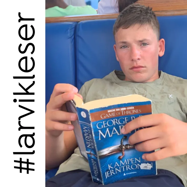 En gutt sitter og leser i en bok. Foto