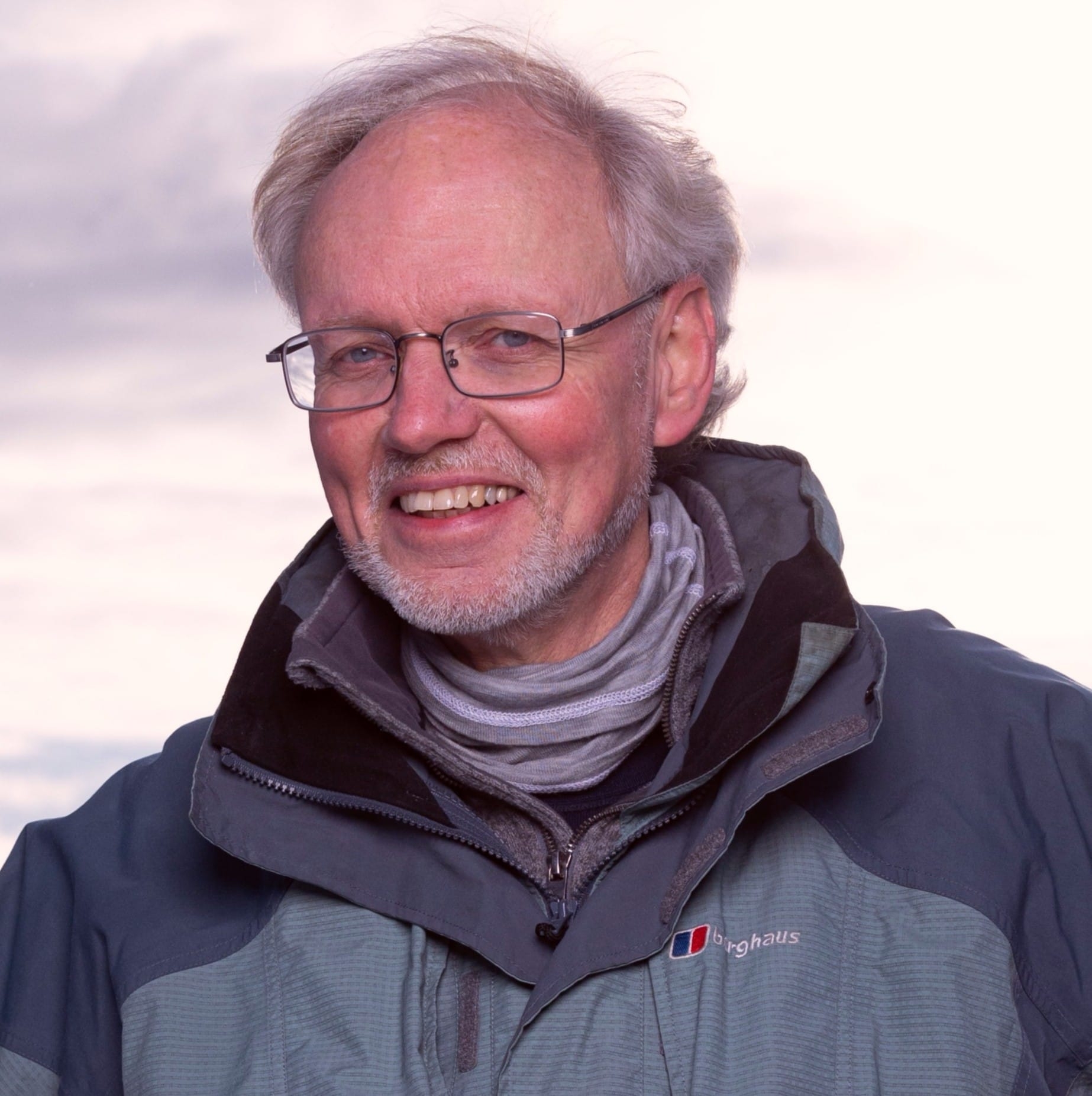 Portrettfoto av smilende mann med briller og vinterjakke