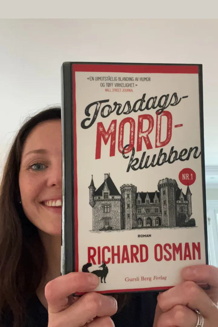 Halve ansiktet til en av bibliotekets ansatte, synes bak bokomslaget til krimboka Torsdagsmordklubben. Hun har langt mørkt hår og smiler.