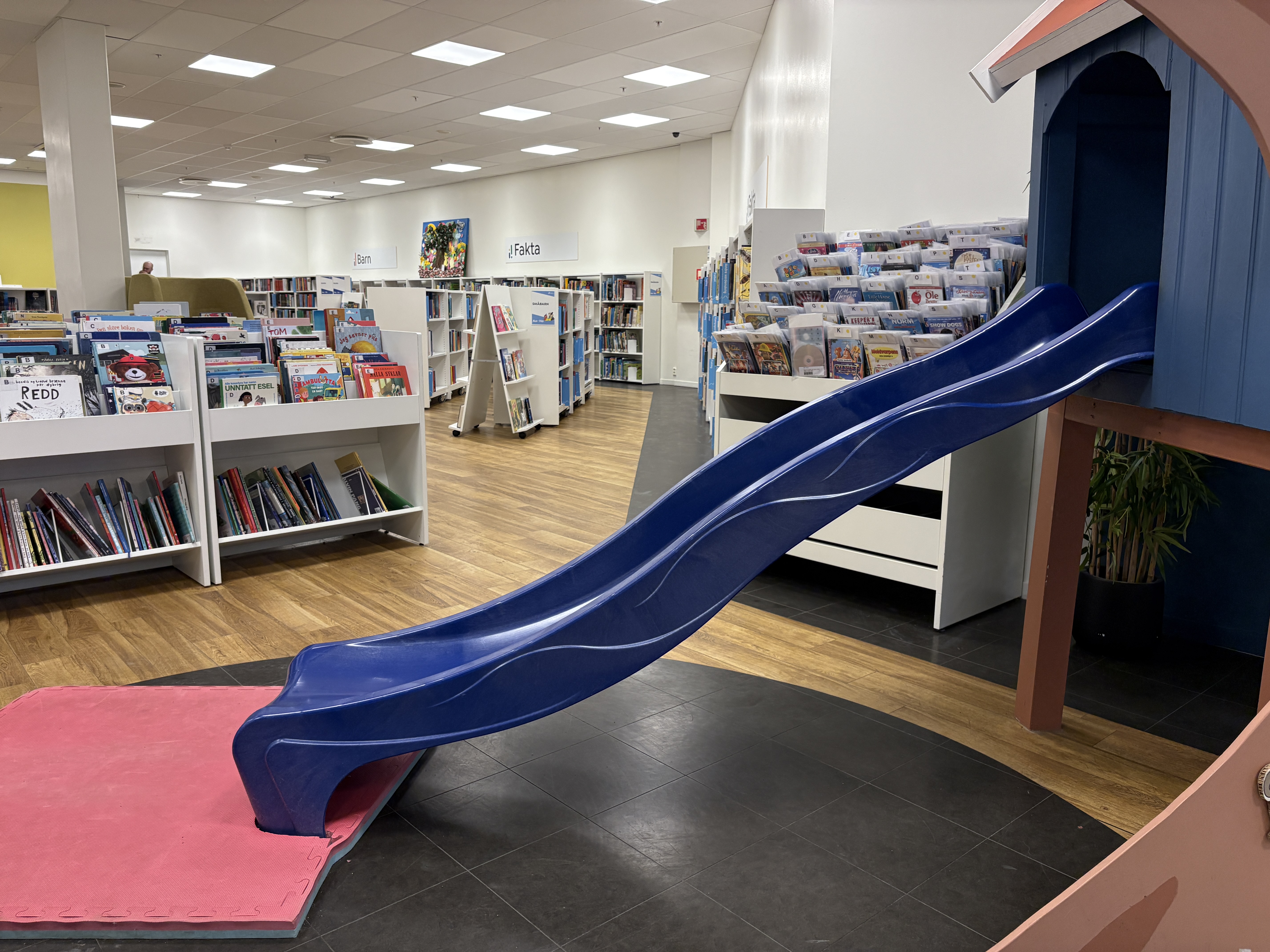 Bildet viser ei sklie i forgrunnen og bibliotekets barneavdeling med bokhyller i bakgrunnen. Foto