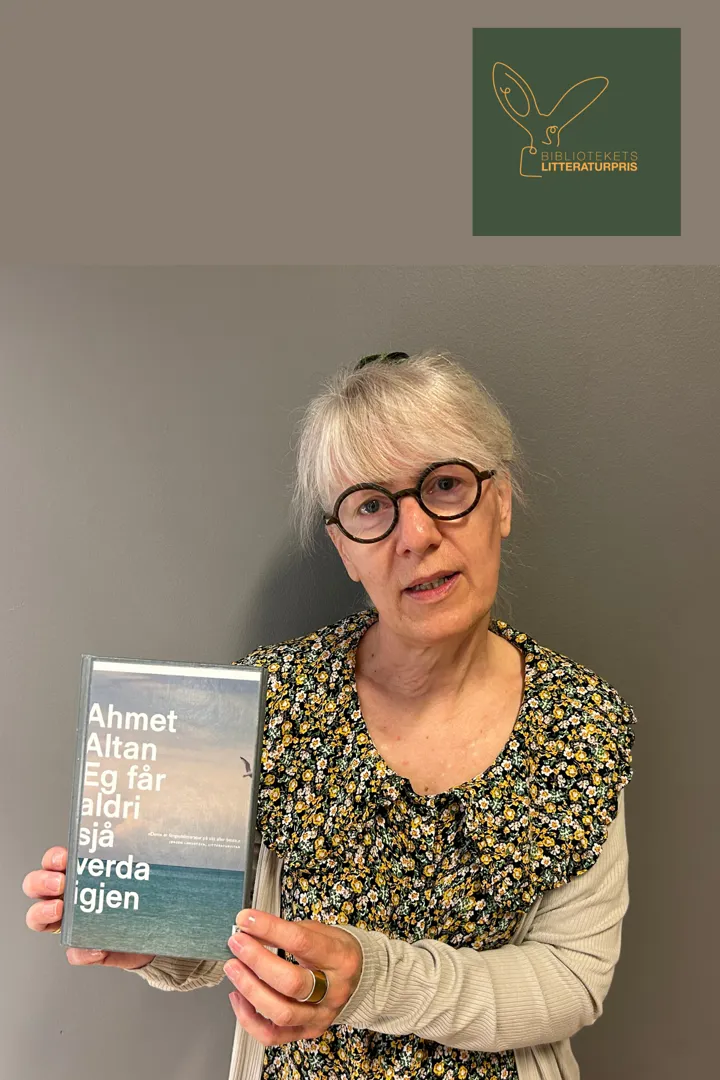 Bibliotekets ansatte, Helga, står foran en brun vegg, hun holder boka Eg får aldri sjå verda igjen i hendene. Foto.