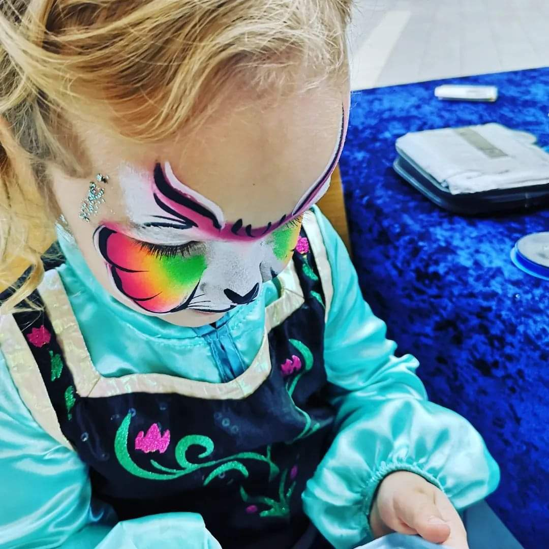 Et barn med ansiktsmaling; hun er malt som et dyr. Foto