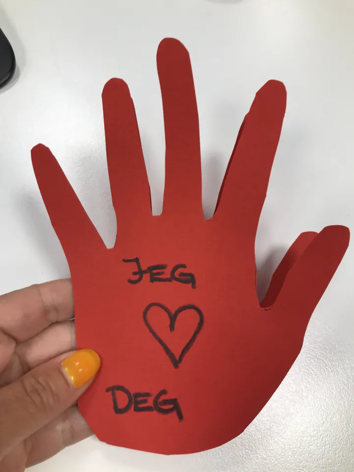 Rød hånd i papir, teksten jeg (hjerte) deg er skrevet på. Foto