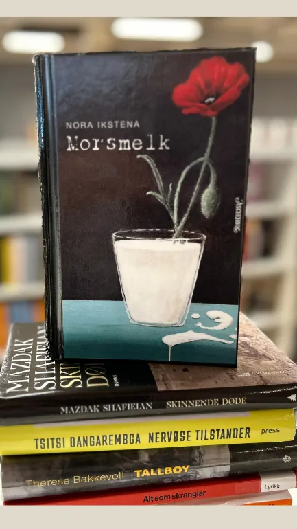 En stabel med bøker. På toppen av stabelen står boka Morsmelk. Omslaget viser et glass med melk med en rød blomst oppi.