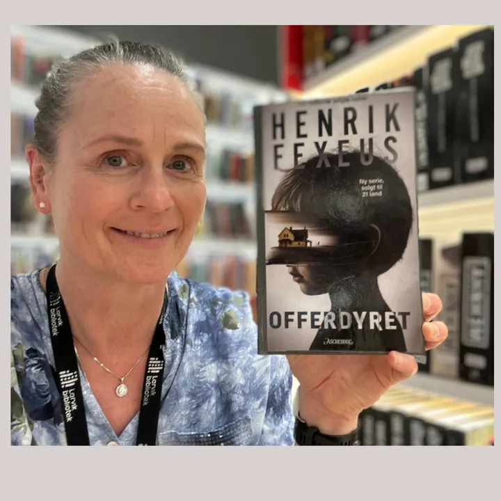 Foto av bibliotekansatt som viser frem boka Offerdyret sin forside.
