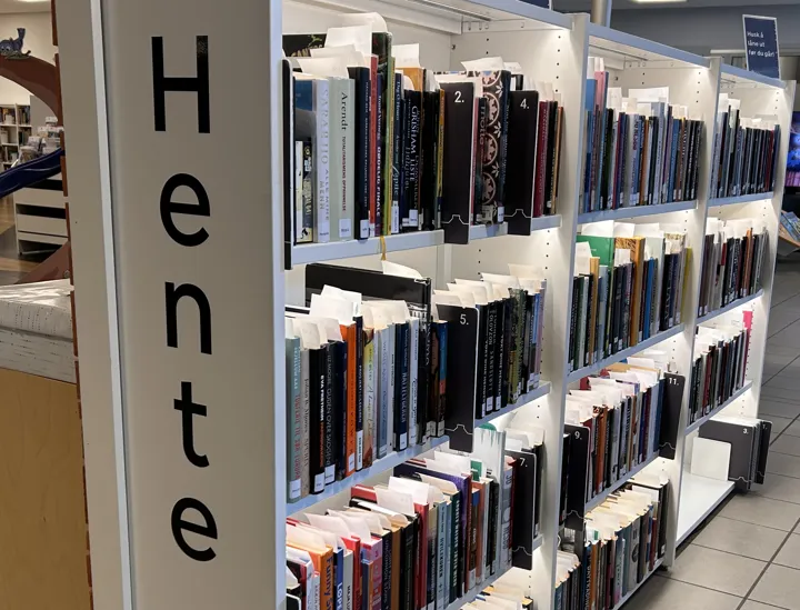 Hentehylle: bokbylle med skilt "hente". Foto
