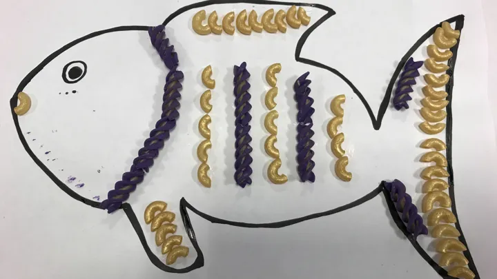 En fisk med fint pastamønster. Tegning med pålimt pasta. Foto