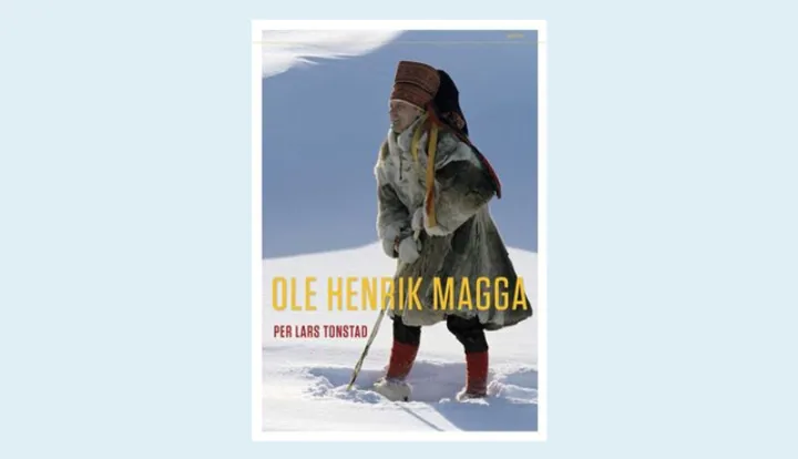 Bokomslag: Foto av en mann som er kledd i reinsdyrpels, fargerik lue og med en stav i hånden. Han står på hvit snø og bak er himmelen blå.