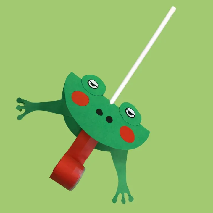 En grønn frosk med lang rød tunge, og et sugerør som stikker ut. Frisken er laget av papir. Foto