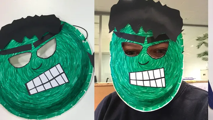 En person har på seg en Hulken-maske laget av papptallerken og dekorert med tusj og papir. Foto