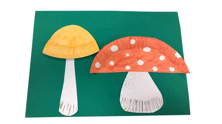 To sopp laget av papptallerkener. En med gul hatt og en med rød hatt med prikker. Foto