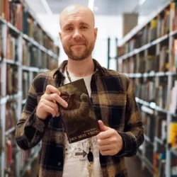 Foto av biblioteksansatt som viser frem boka Den siste viking.