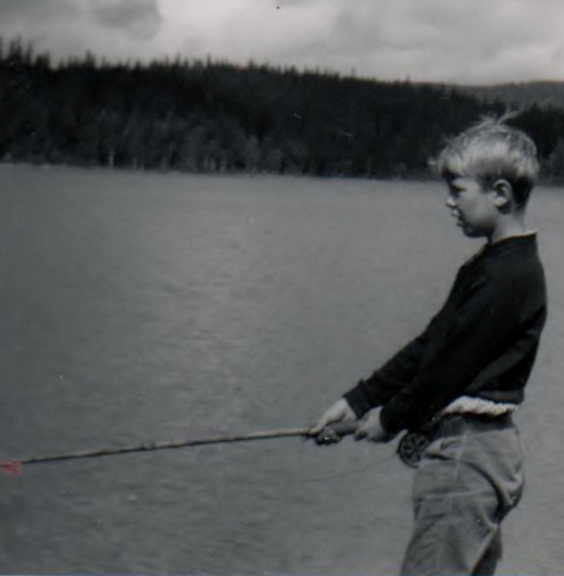 Foto viser forfatteren som ung gutt. Gutten står ved et vann med en fiskestang i hendene. Svart/hvitt foto.