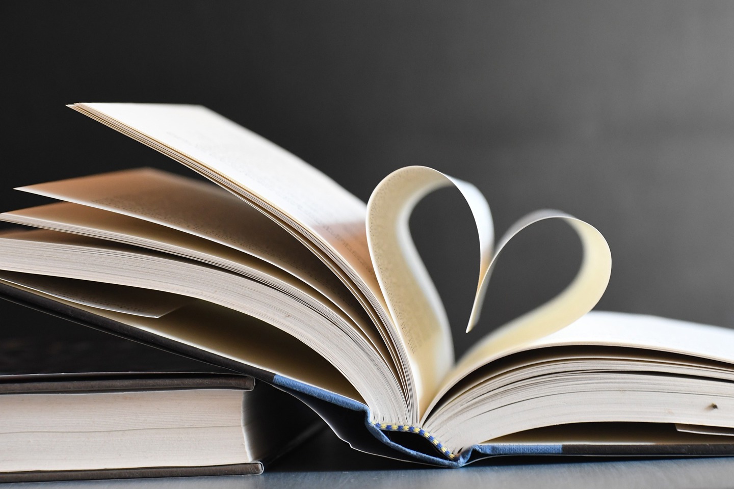 En bok ligger åpen, to av sidene er bøyd slik at de sammen danner et hjerte. Bilde fra Pixabay